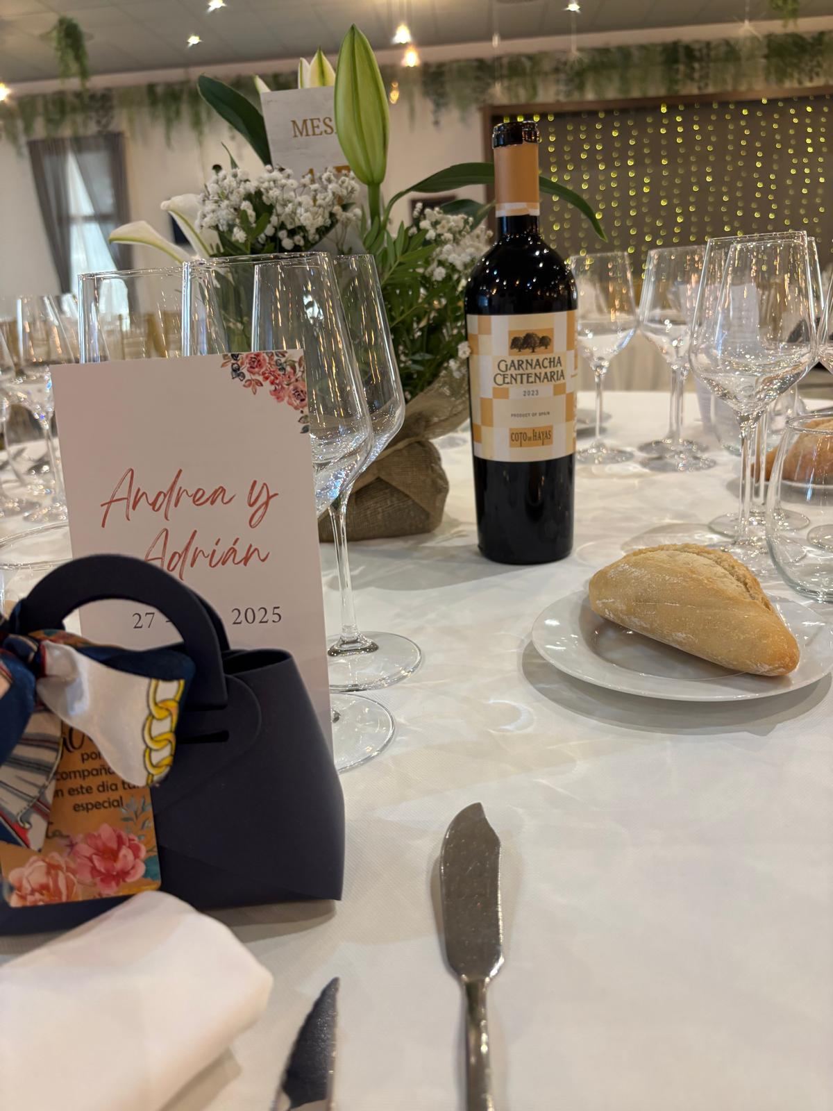 Mesa de banquete de boda con minuta personalizada, vino y flores