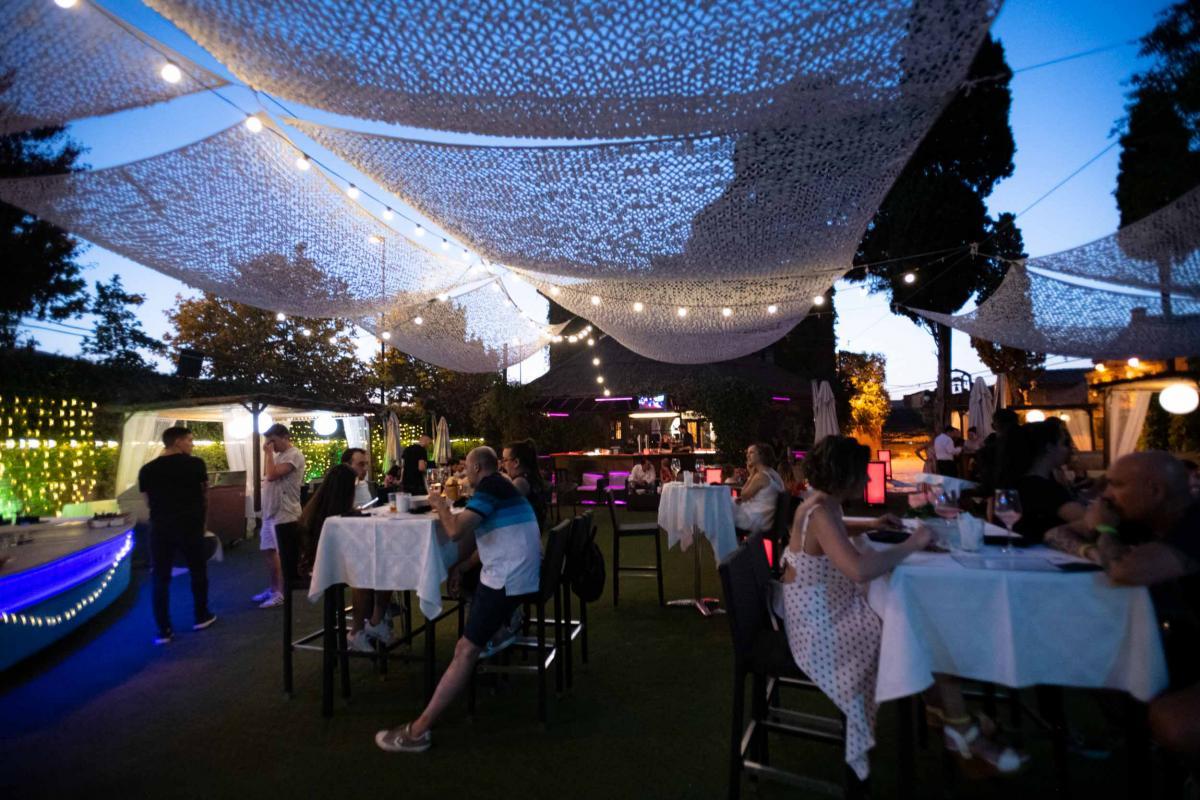 Cena al anochecer en la terraza bajo toldos y guirnaldas de luces