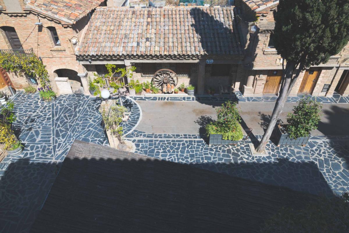 Patio empedrado con plantas y tejados del palacio vistos desde arriba