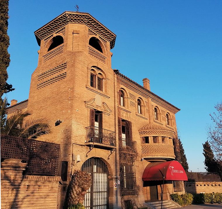 Torre de ladrillo del palacio y entrada con toldo rojo al atardecer